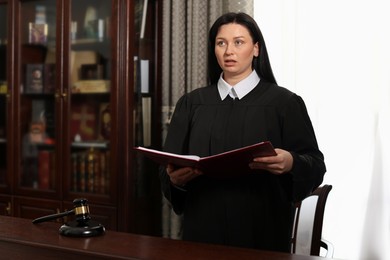 Photo of Judge with folder of documents at table in courtroom