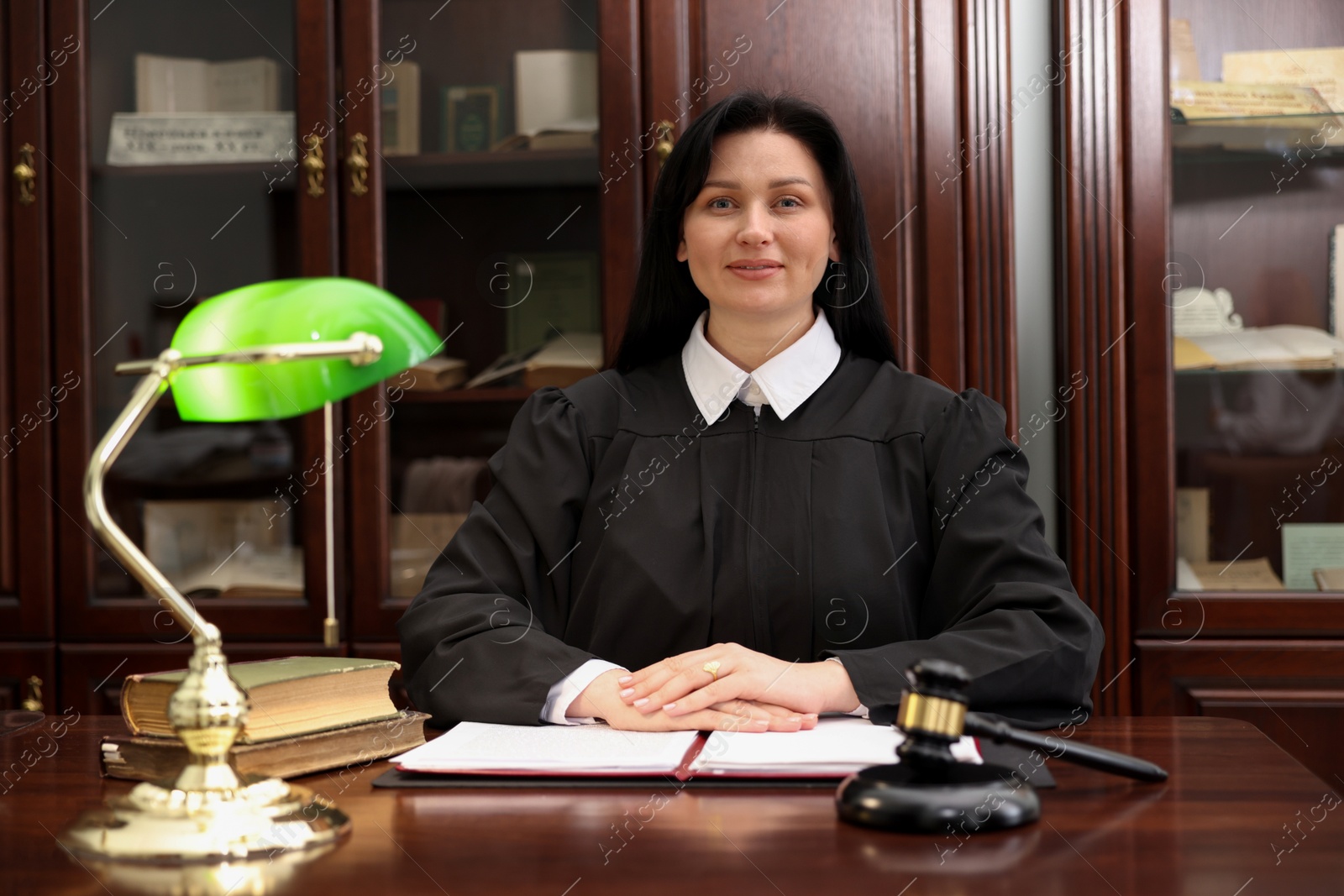 Photo of Judge in court dress at wooden table indoors