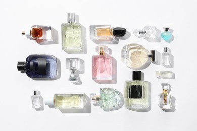 Photo of Different aromatic perfumes in bottles on white background, flat lay