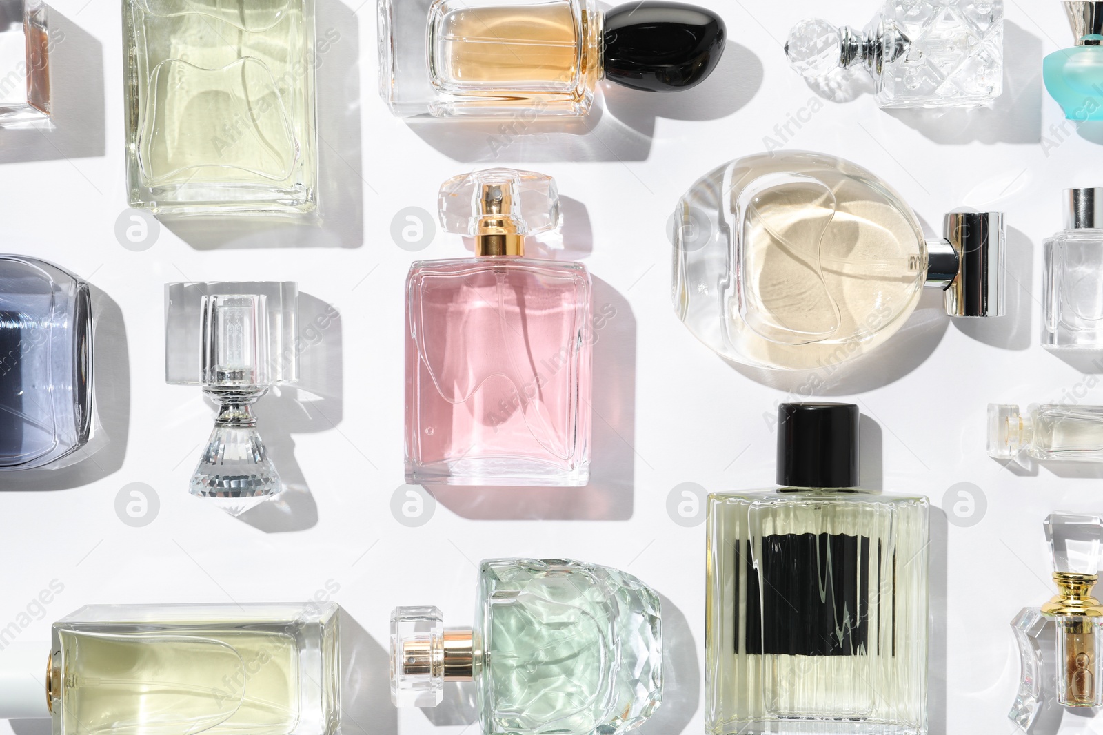 Different aromatic perfumes in bottles on white background, flat lay Photo of Different aromatic perfumes in bottles on white background, flat lay
