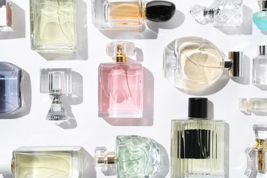 Photo of Different aromatic perfumes in bottles on white background, flat lay