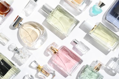 Photo of Different aromatic perfumes in bottles on white background, flat lay