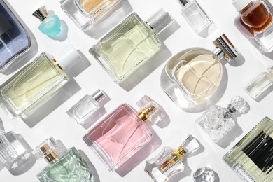 Photo of Different aromatic perfumes in bottles on white background, flat lay