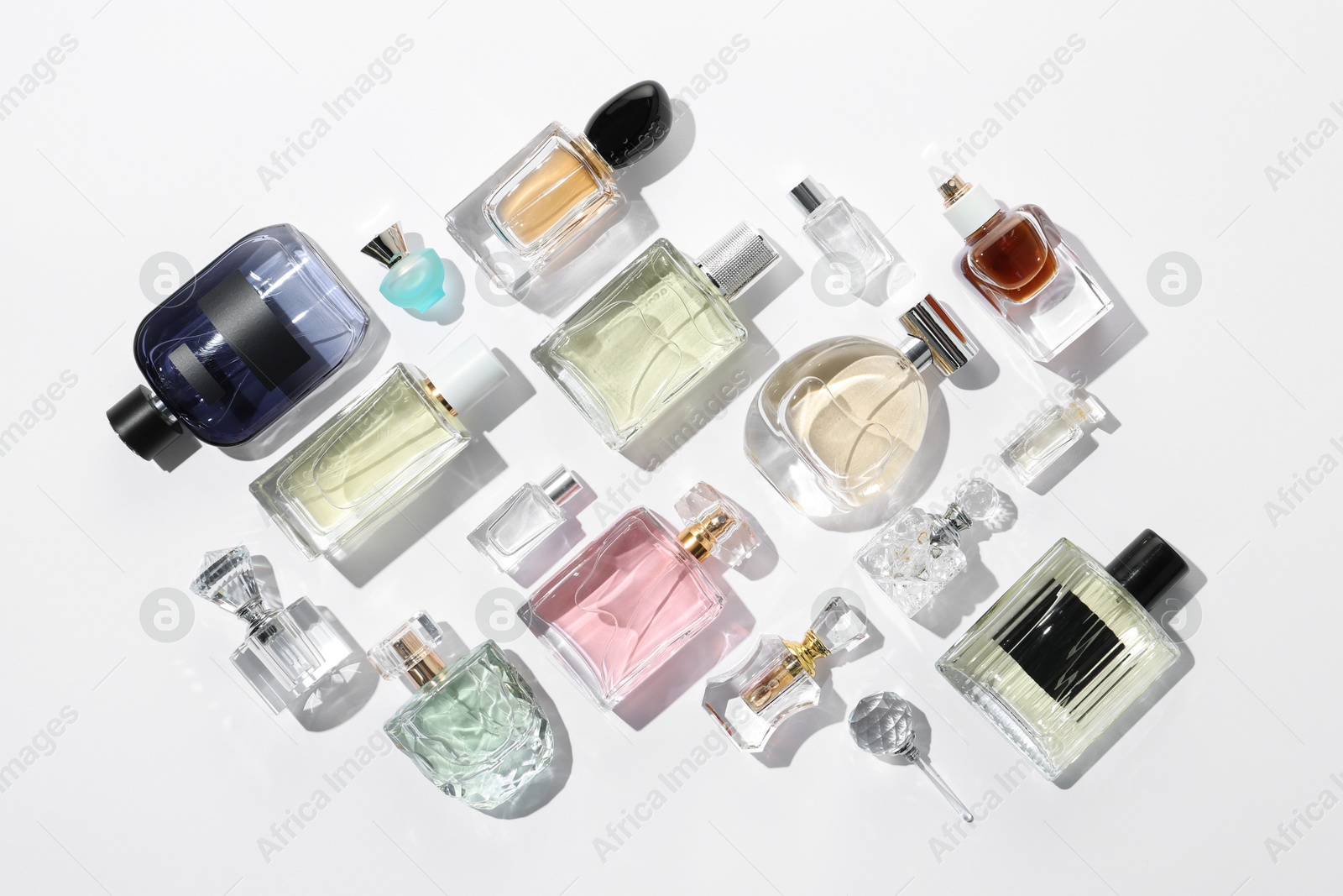 Different aromatic perfumes in bottles on white background, flat lay Photo of Different aromatic perfumes in bottles on white background, flat lay