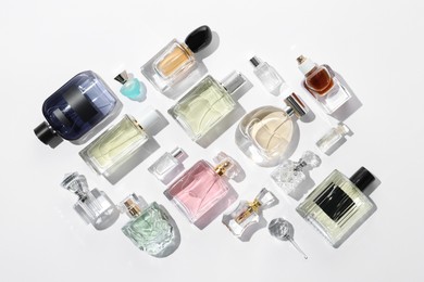 Photo of Different aromatic perfumes in bottles on white background, flat lay