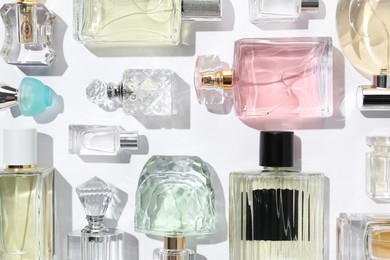 Photo of Different aromatic perfumes in bottles on white background, flat lay