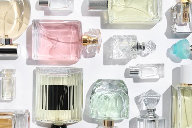 Photo of Different aromatic perfumes in bottles on white background, flat lay