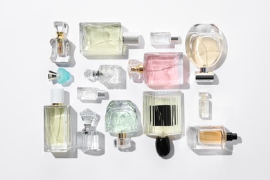 Photo of Different aromatic perfumes in bottles on white background, flat lay