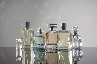 Photo of Different luxury perfumes on glass surface. Bokeh effect