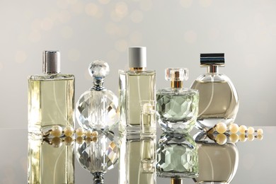 Photo of Different luxury perfumes on glass surface. Bokeh effect