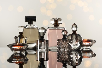 Photo of Different luxury perfumes on glass surface. Bokeh effect