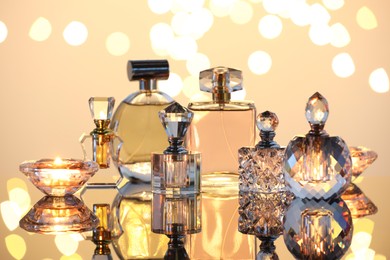 Photo of Different luxury perfumes on glass surface. Bokeh effect