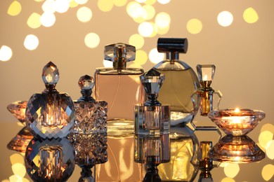 Photo of Different luxury perfumes on glass surface. Bokeh effect