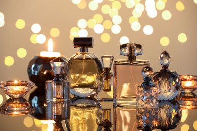 Photo of Different luxury perfumes on glass surface. Bokeh effect