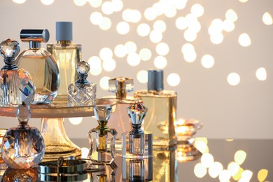 Photo of Different luxury perfumes on glass surface. Bokeh effect