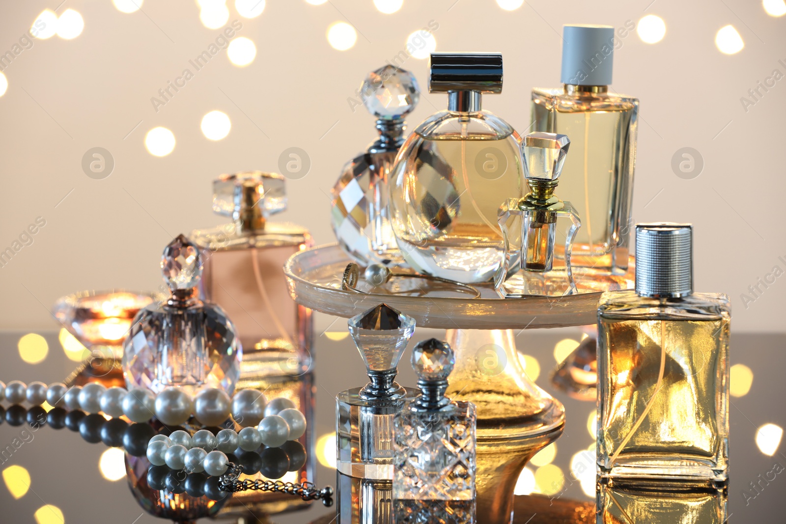 Different luxury perfumes on glass surface, closeup. Bokeh effect Photo of Different luxury perfumes on glass surface, closeup. Bokeh effect