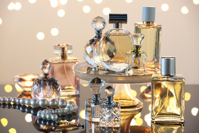 Photo of Different luxury perfumes on glass surface, closeup. Bokeh effect