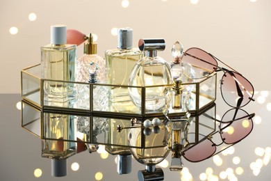 Photo of Different luxury perfumes on glass surface. Bokeh effect