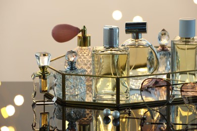 Photo of Different luxury perfumes on glass surface, closeup. Bokeh effect