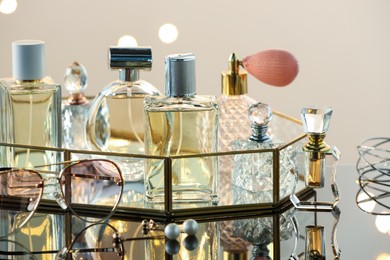 Photo of Different luxury perfumes on glass surface, closeup. Bokeh effect