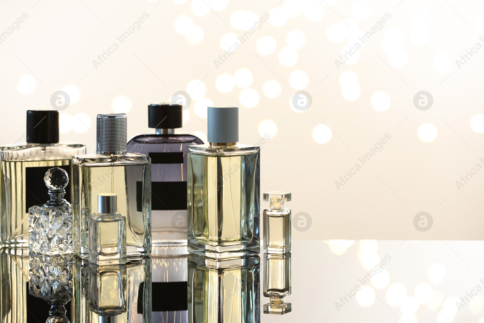 Different luxury perfumes on glass surface, space for text. Bokeh effect Photo of Different luxury perfumes on glass surface, space for text. Bokeh effect