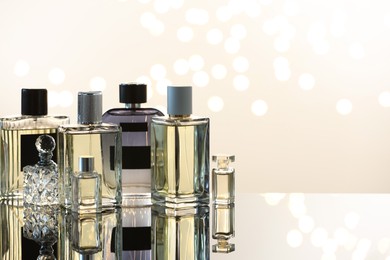 Photo of Different luxury perfumes on glass surface, space for text. Bokeh effect