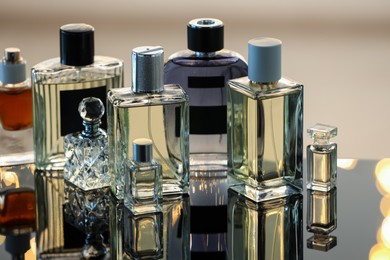 Photo of Different luxury perfumes on glass surface, closeup