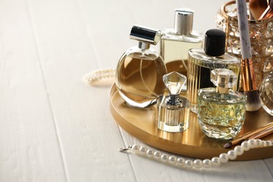 Photo of Different luxury perfumes on white wooden table. Space for text