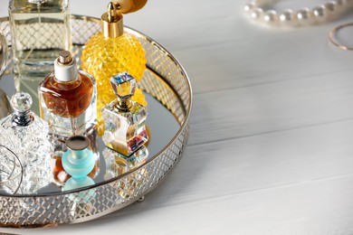 Photo of Different luxury perfumes on white wooden table. Space for text