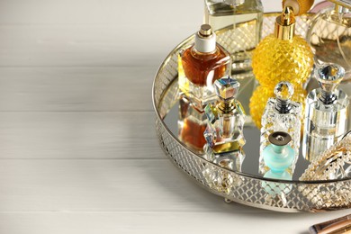 Photo of Different luxury perfumes on white wooden table. Space for text