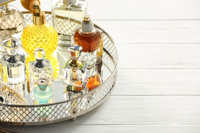 Photo of Different luxury perfumes on white wooden table. Space for text