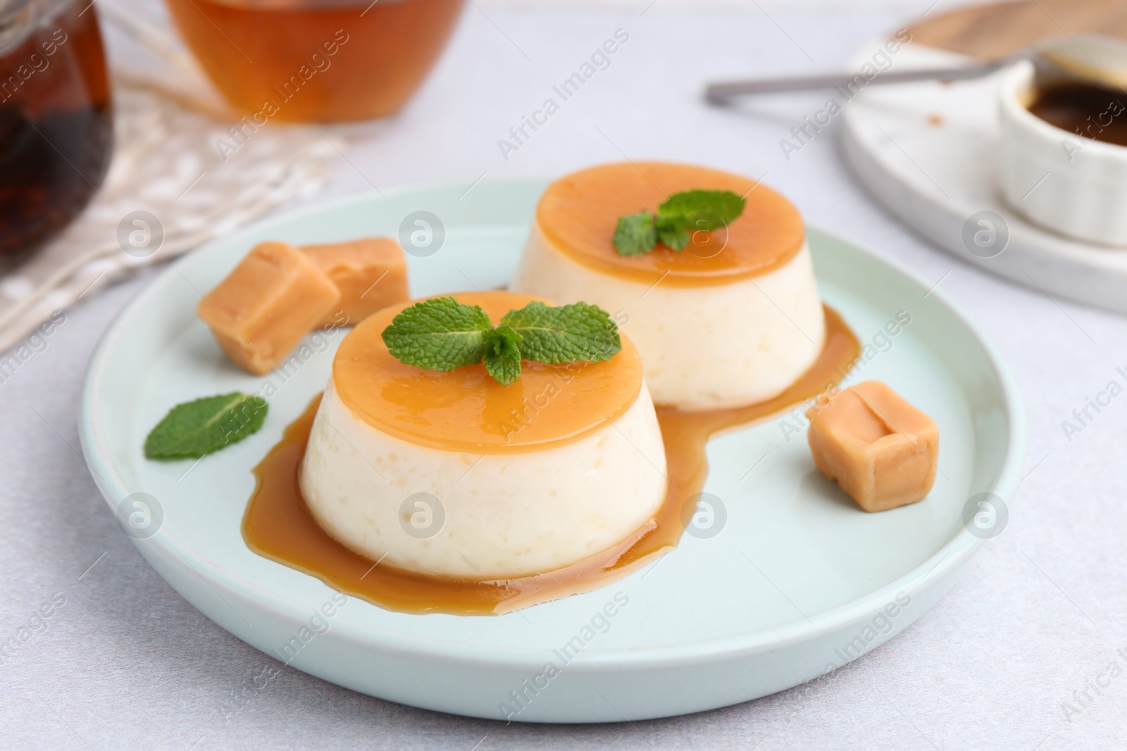 Photo of Tasty puddings with caramel sauce served on white table, closeup