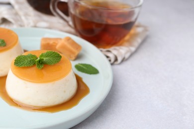 Photo of Tasty puddings with caramel sauce served on white table, closeup. Space for text