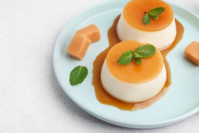 Photo of Tasty puddings with caramel sauce served on white table, closeup. Space for text