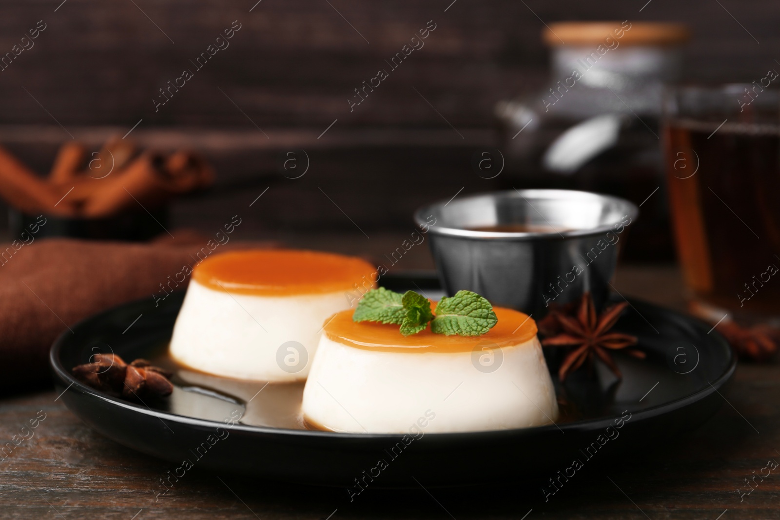 Photo of Tasty puddings with caramel sauce served on wooden table, closeup