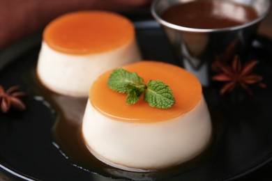 Photo of Tasty puddings with caramel sauce served on table, closeup