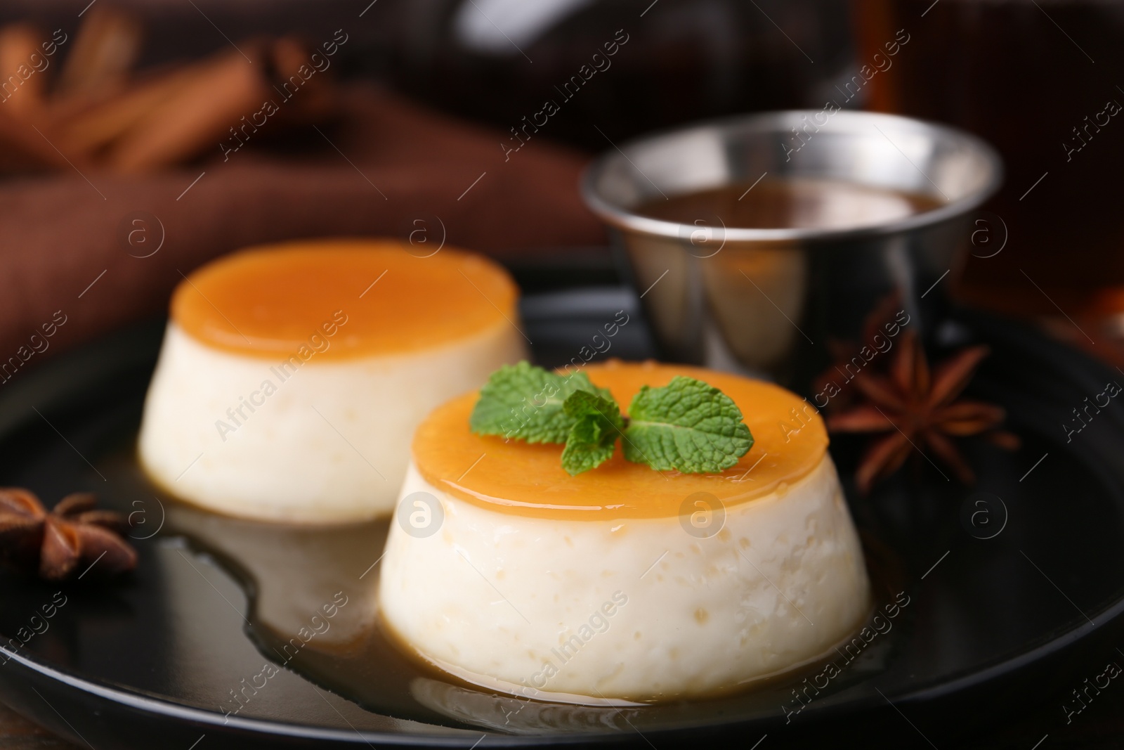 Photo of Tasty puddings with caramel sauce served on table, closeup