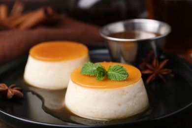 Photo of Tasty puddings with caramel sauce served on table, closeup