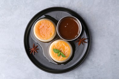 Photo of Tasty puddings with caramel sauce served on light grey table, top view