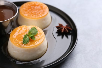 Photo of Tasty puddings with caramel sauce served on light grey table, closeup. Space for text