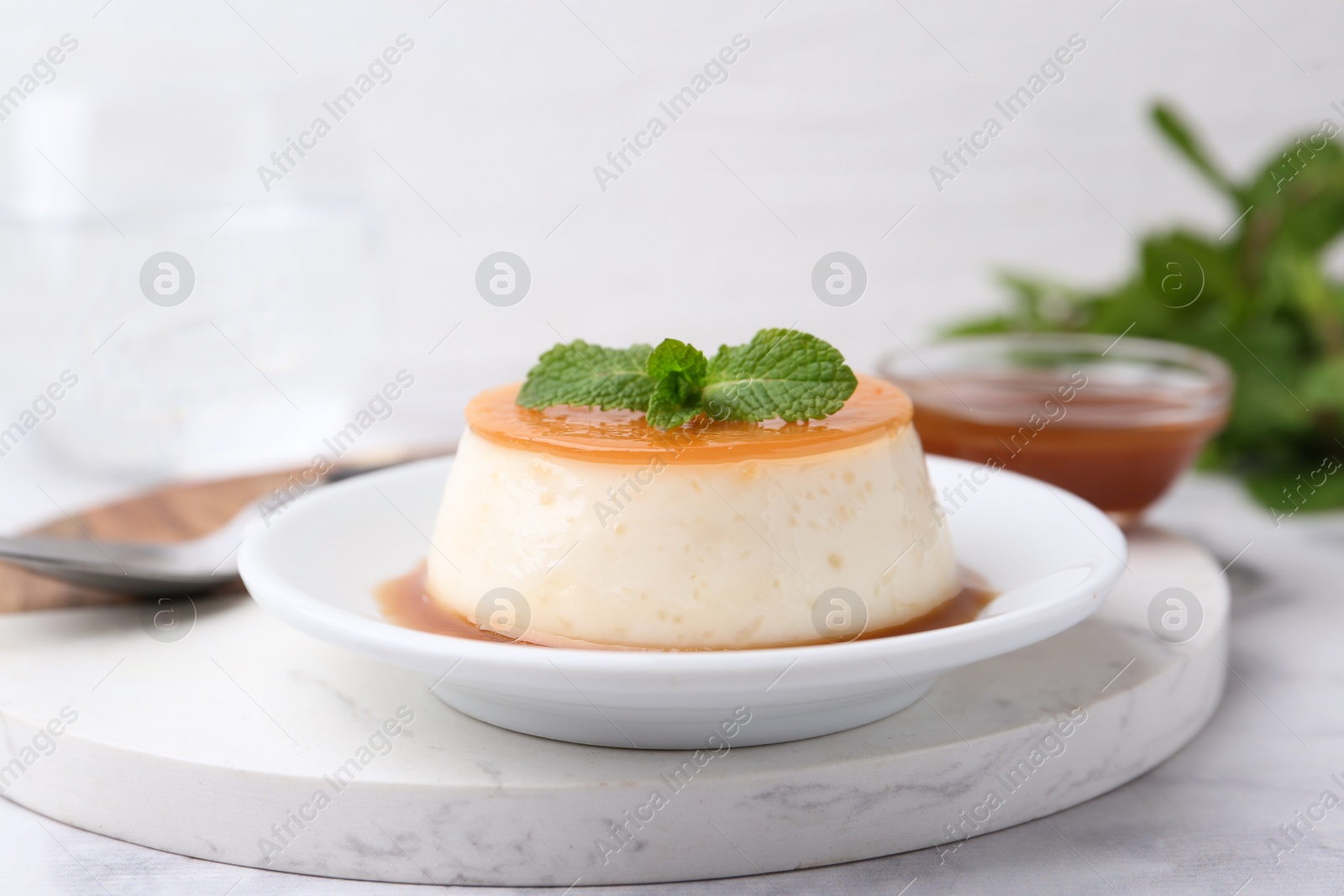 Photo of Tasty pudding with caramel sauce served on white marble table, closeup