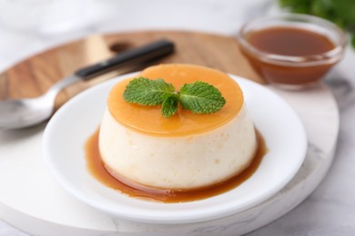 Photo of Tasty pudding with caramel sauce served on white marble table, closeup