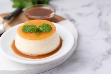 Photo of Tasty pudding with caramel sauce served on white marble table, closeup. Space for text