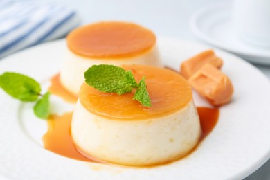 Photo of Tasty puddings with caramel sauce served on table, closeup