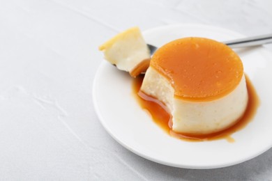 Photo of Tasty pudding with caramel sauce served on white textured table, closeup. Space for text