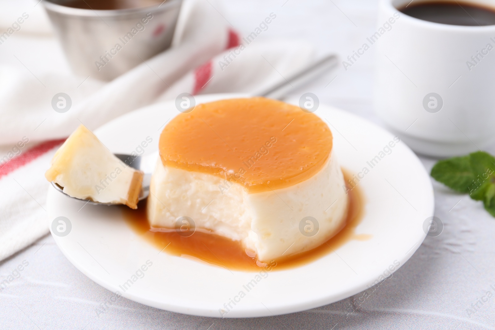 Photo of Tasty pudding with caramel sauce served on white textured table, closeup