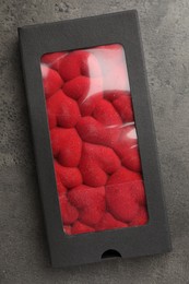 Photo of Chocolate bar decorated with hearts in box on grey table, top view