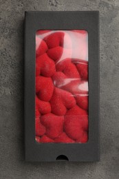 Photo of Chocolate bar decorated with hearts in box on grey table, top view