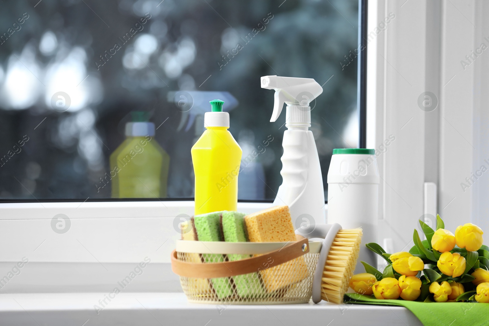 Photo of Spring cleaning. Detergents, supplies and yellow tulips near window indoors, space for text