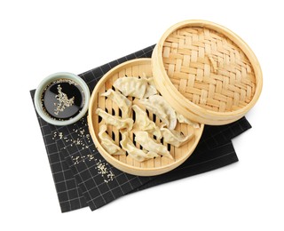 Photo of Tasty boiled gyoza (dumplings) with soy sauce and sesame on white background, top view